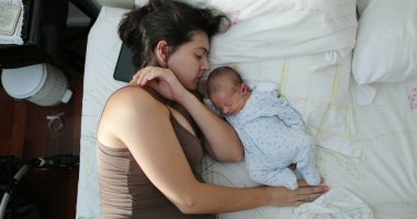 Baby newborn sleeping next to mother candid