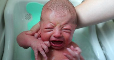 Washing newborn baby bathing in warm water