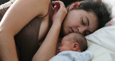 Candid mom and baby asleep in bed together