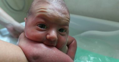 Washing newborn baby infant, closeup of baby face bathing