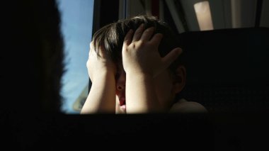 Yorgun Çocuk Hareket Eden Trende Ovalanıyor, Seyahat ederken uykudan uyanıyor, kendini güneş ışınlarından koruyor