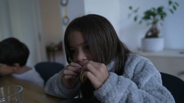 Little girl eating pancake food in the morning, casual domestic lifestyle scene of children at meal table wearing sweater