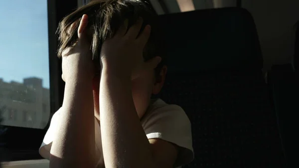 Exhausted Child Rubbing Eyes on Moving Train, Waking from Nap by window while traveling, protecting himself from sun rays