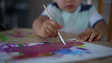 Yaratıcı sanatsal oturum sırasında suluboya ve boya fırçasıyla çocuk el resmine yakın çekim, sanatla uğraşan bir çocuğun çocukluk anı