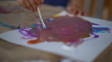 Çocuk eli, suluboya resimli boya fırçası kullanıyor.