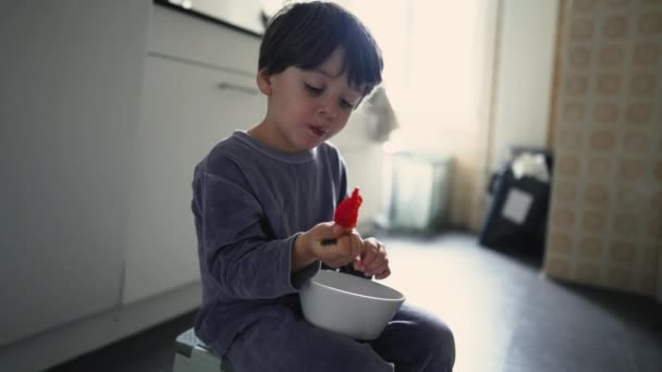 Kind Ontbijten Keukenvloer Houden Kom Hand Eten Van Aardbeienfruit Tijdens — Stockvideo