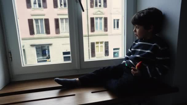 Niño Sentado Junto Ventana Mirando Vista Con Mirada Contemplativa Reflexiva — Vídeos de Stock
