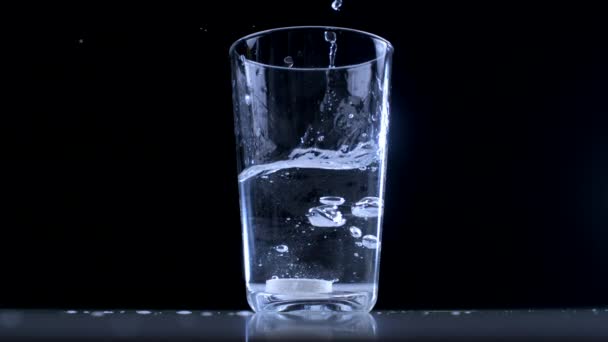 ガラスカップの水に発熱性ビタミンC錠を落とす 黒い背景 — ストック動画