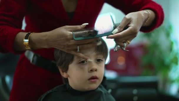 リトルボーイは サロンでヘアカットを取得 プロのヘアスタイリストの組み合わせと子供の髪を切断 — ストック動画