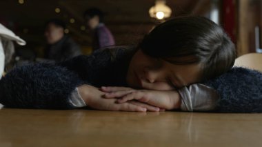 Kafası masaya uzanmış üzgün bir çocuk. Lokantada melankolik 8 yaşındaki bir çocuğa yakın duruyor.