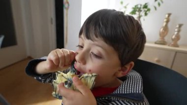 Yemek saatinde püre kaplı mutfak aletlerini yalayan aç küçük çocuk. Sevimli çocuk kelebek çırpma aletinden ezilmiş patates yiyor.