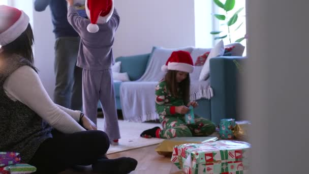 Οικογενειακά Χριστούγεννα Πρωί Παιδιά Άνοιγμα Δώρα Αγόρι Κόκκινο Καπέλο Κρατώντας — Αρχείο Βίντεο