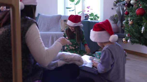 Boże Narodzenie Rano Salonie Rodziną Prezenty Dzieci Czerwonych Kapeluszach Otwierających — Wideo stockowe