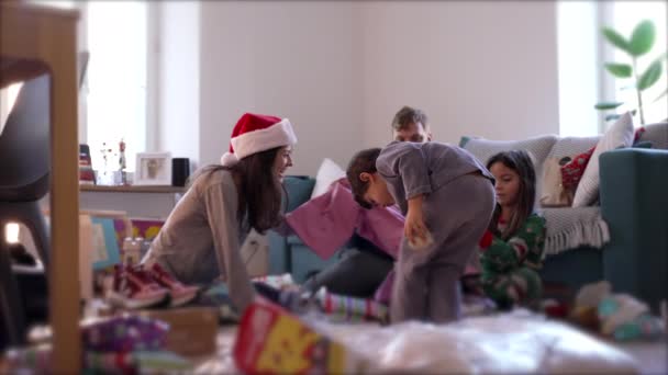 家人在早上拆开圣诞礼物 家长和孩子们穿着睡衣在12月的假期里在客厅里享用开幕礼物 — 图库视频影像