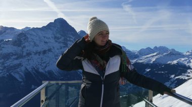 Alpine Joy - Grindelwald 'ın İlk Tepe Görünüm Platformu' ndaki Kadın Göz kamaştırıcı Alp Arkaplanı ile Kameraya Gülümsüyor