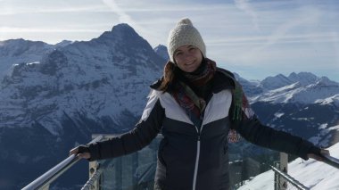 İkonik platformda dikilen kadının portresi Grindelwald 'ın ilk göz alıcı manzarası. Kış kıyafetleri giymiş ve kameraya gülümsüyor.