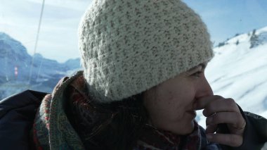 Kış mevsiminde soğuk giysiler içinde burnunu kaşıyan bir kadın.