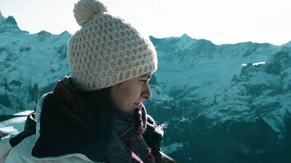 Mindful woman enjoying the Swiss Alps overlooking scenic mountain covered in snow backdrop. Pensive introspective person in 30s contemplating nature