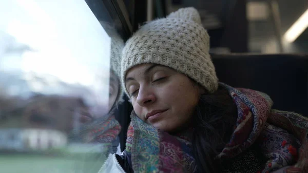 Woman falling asleep while traveling by train. Female passenger leaning on window closes eyes while traveling in motion