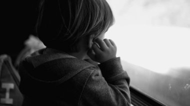 Trenle seyahat ederken üzgün, düşünceli bir çocuk. Depresyondaki yolcu cam pencereye yaslanmış melankolik ve endişeli hissederken siyah ve beyaz yolda gidip geliyor.