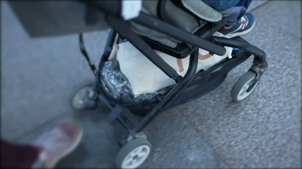 Stroller closeup in motion with child seated. Baby carriage wheels going being pushed forward