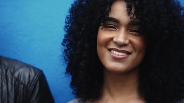Одна Счастливая Молодая Латиноамериканка Вьющимися Волосами Улыбается Камеру Синем Фоне — стоковое видео