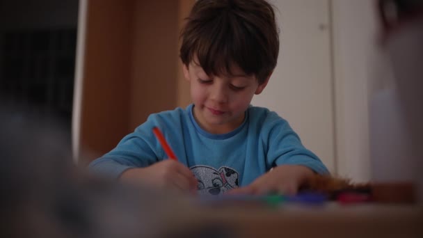 一人の幸せな少年が 就寝前の夕方にパジャマを着て家で絵を描いている 紙の笑顔で創造的な着色に従事する子供 — ストック動画