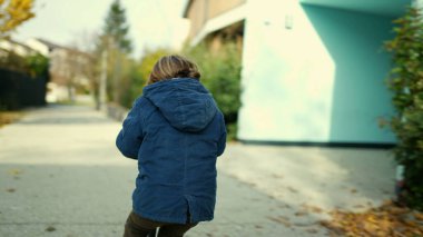 Mutlu çocuk dışarıda oyuncak scooter kullanıyor, 3 yaşındaki küçük bir çocuk güz gününde gün ışığında ileri doğru gidiyor.