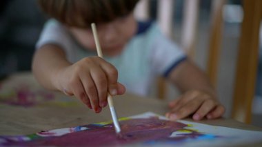 Çocuk eli, suluboya resimli boya fırçası kullanıyor.