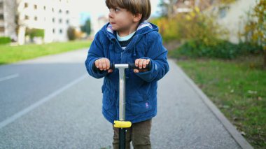 Aktif çocuk oyuncak scooter kullanıyor, yeşil yolda şehircilik alternatif hareket kabiliyeti
