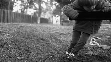 Park salıncağına yaslanan yalnız küçük bir çocuk dışarıda salıncak sallıyor tek renkli ve beyaz bir parkın ortasında yalnızlık çekiyor. Çocukluk depresyonu kavramı