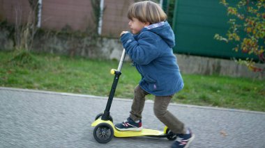 Aktif Üç Yaşındaki Çocuk Üç Tekerli Scooter 'la gezintiden keyif alıyor.