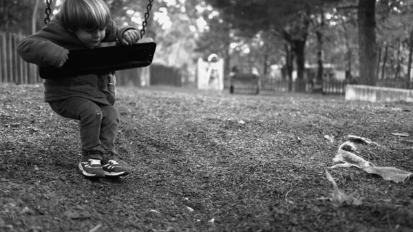 Park salıncağına yaslanan yalnız küçük bir çocuk dışarıda salıncak sallıyor tek renkli ve beyaz bir parkın ortasında yalnızlık çekiyor. Çocukluk depresyonu kavramı
