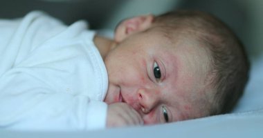 Cute happy newborn baby smiling feedling joy, infant first week of life in bed