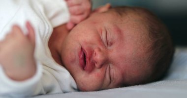 Cute adorable newborn baby waking up opening eyes and falling back to sleep again