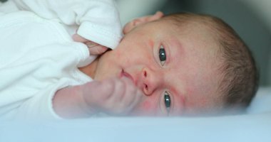 Infant newborn baby lying in bed observing