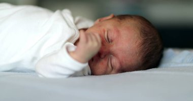 Baby newborn close-up face waking up and opening eyes