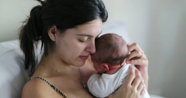 Mom holding newborn baby showing love and affection