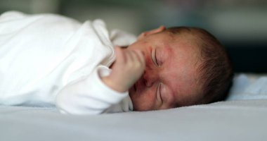 Baby newborn close-up face waking up and opening eyes