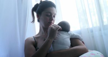 Affectionate mother holding newborn baby next to window curtain
