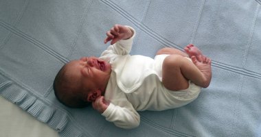Newborn baby infant crying in bed