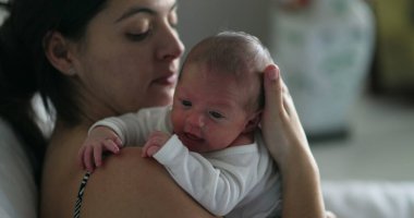 Mother holding tiny newborn frafile infant during first week of life
