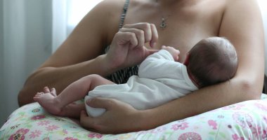 Mother holding newborn baby close-up breastfeeding