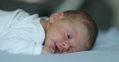 Newborn baby infant laying in bed being adorable and cute