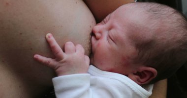 Mother breastfeeding newborn baby, infant suckling feeding during first week of life