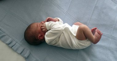 Newborn baby infant during first week of life, baby laid in bed seen from above
