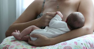Mother holding newborn baby close-up breastfeeding