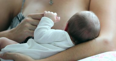 Mother holding newborn baby in her arms holding little finger
