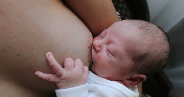 Newborn baby asleep while holding on mother breast