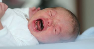 Newborn baby lying in beed looking to camera, first week of life
